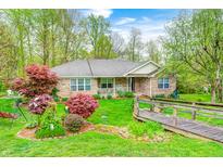 Charming brick home with lush landscaping, including a wooden bridge and colorful shrubs at 8329 S Christian Dr, Nineveh, IN 46164