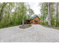 Charming log cabin exterior with a gravel driveway and a backdrop of lush green trees at 1630 Hinson Rd, Martinsville, IN 46151
