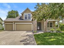 Charming two-story home with stone accents, three-car garage, covered porch, and a well-manicured lawn at 19552 Wagon Trail Dr, Noblesville, IN 46060