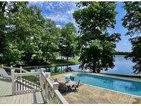 Stunning pool with lakeside views, surrounded by mature trees and a deck with outdoor seating at 2001 E Ely Ct, Martinsville, IN 46151