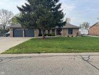 Charming brick home with a well-manicured lawn, mature tree, and a spacious two-car garage at 2550 16Th St, Columbus, IN 47201