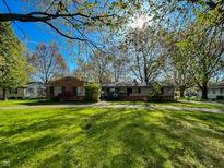 Charming single story home with brick and siding, circular driveway, and mature trees on a sunny lot at 4305 Lincoln Rd, Indianapolis, IN 46228