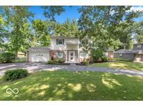Charming two-story home with a brick facade, attached garage and a beautifully landscaped front yard at 7546 Lindenwood Dr, Indianapolis, IN 46227