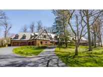 Charming Tudor-style home with a brick facade, slate roof, and a circular driveway at 8103 N Pennsylvania St, Indianapolis, IN 46240