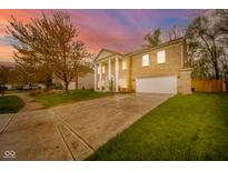 Classic brick home with a grand entrance, columns, and a beautiful landscaped front yard against a colorful sunset at 10090 Eagle Eye Way, Indianapolis, IN 46234