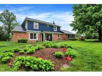 Charming two-story home featuring a brick facade and a well-manicured lawn with lovely flower beds at 1095 Williamsburg Ln, Zionsville, IN 46077