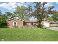 Charming brick home with attached garage and lush green lawn in a well-maintained neighborhood at 1416 Wellington Ave, Indianapolis, IN 46219