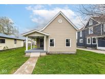 Charming tan single-story home featuring a welcoming front porch and well-manicured lawn at 1523 S K St, Elwood, IN 46036