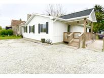 Charming single-story home with white siding, black shutters and a gravel driveway at 223 E 53Rd St, Anderson, IN 46013