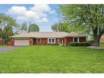 Charming brick ranch home features a well-manicured lawn and attached two-car garage on a sunny day at 4044 Roamin Dr, Greenwood, IN 46142