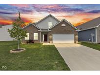 Charming brick home featuring an attached two-car garage and a well-manicured lawn at 5423 Maywood Dr, Whitestown, IN 46075
