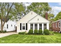 Charming home featuring bright siding, black shutters, a brick chimney, mature landscaping, and a well-manicured lawn at 6167 Ralston Ave, Indianapolis, IN 46220