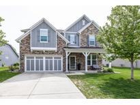 Charming two-story home boasts stone and gray siding, a well-manicured lawn, and an attached two-car garage at 755 Canberra Blvd, Westfield, IN 46074