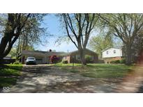 Charming one-story brick home with mature trees and a covered carport on a sunny day at 7629 Walton Dr, Indianapolis, IN 46214