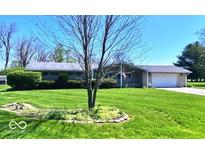 Ranch home with an attached garage has a large front lawn and landscaping at 8604 W Tulip Tree Dr, Muncie, IN 47304