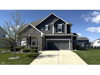 Beautiful two-story home with gray siding, stone accents, well-manicured lawn, and an attached two-car garage at 15406 Forest Glade Dr, Fishers, IN 46037