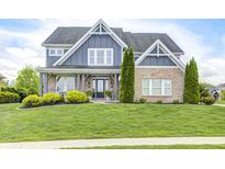 Charming two-story home with a brick and blue facade, beautiful landscaping, and inviting front porch at 3387 Keystone Pass, Plainfield, IN 46168