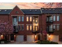 Charming brick townhomes featuring private garages and balconies against a beautiful sunset backdrop at 548 Lockerbie N Cir, Indianapolis, IN 46202