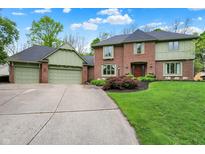 Traditional brick home with a three-car garage, manicured lawn, and mature landscaping at 13494 Dallas Ln, Carmel, IN 46033