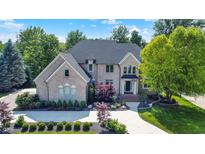 Elegant brick home boasts a manicured lawn, beautiful landscaping, and a circular driveway for a grand entrance at 13934 Salsbury Creek Dr, Carmel, IN 46032