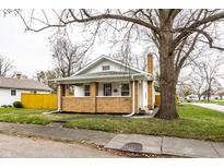 Charming brick home with a cozy front porch and well-maintained lawn at 1451 N Grant Ave, Indianapolis, IN 46201
