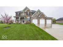 Beautiful two-story brick home featuring a manicured lawn and attached three-car garage at 2432 Scarlet Oak Dr, Avon, IN 46123