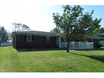Single story brick home with a white picket fence and lush green lawn at 2630 Wedgewood Dr, Columbus, IN 47203