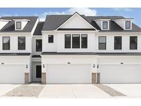 New construction townhome featuring a crisp white exterior, black trim windows, and a convenient two-car garage at 3305 Noriker Ln, Zionsville, IN 46077