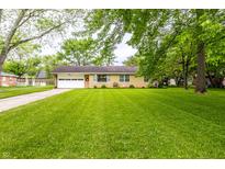 Charming single-story home with lush lawn and an attached garage at 5450 Fenmore Rd, Indianapolis, IN 46228