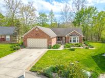 Charming brick ranch home featuring an attached two car garage and manicured lawn at 5615 Burning Tree Ct, Indianapolis, IN 46239