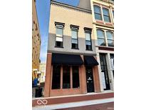 View of the building's stylish brick exterior with black awnings and large windows at 114 S Walnut St, Muncie, IN 47305