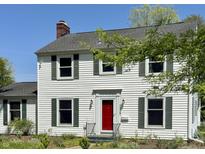 Charming two-story home featuring a bright red front door, white siding, green shutters, and mature landscaping at 2405 Sycamore St, Columbus, IN 47201