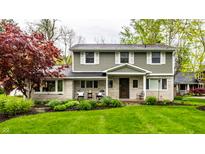 Charming two-story home with a stone facade, manicured lawn, and mature trees at 440 E 82Nd St, Indianapolis, IN 46240