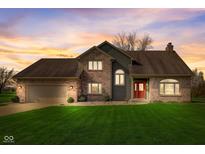 Charming two-story brick home with a well-manicured lawn and a welcoming red front door at sunset at 4940 Sundance Trl, Indianapolis, IN 46239