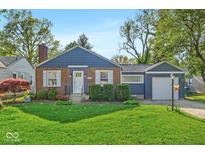 Charming brick home with a well-manicured lawn, lush bushes, and a cozy front porch at 5504 Indianola Ave, Indianapolis, IN 46220