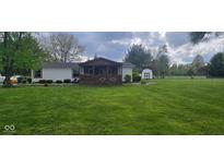 Charming home with a cozy front porch and lush green lawn at 7639 N Frontage Rd, Fairland, IN 46126