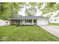 Charming one-story home with a well-manicured lawn and attached garage, complemented by a cozy front porch at 8145 Railroad Rd, Indianapolis, IN 46217