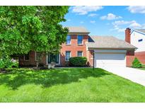 Charming two-story brick home featuring a manicured lawn and mature trees at 10746 Gateway Dr, Fishers, IN 46037