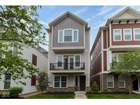 Charming three-story home with a balcony, complemented by manicured landscaping and vibrant greenery at 13323 Susser Way, Fishers, IN 46037