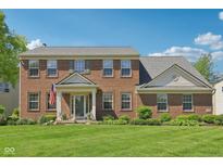 Charming two-story brick home featuring a well-manicured lawn and traditional architectural details at 14162 Nicholas Dr, Carmel, IN 46074