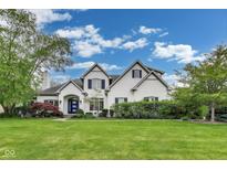 Charming two-story white brick home featuring lush landscaping and a blue front door at 2979 Kings Ct, Carmel, IN 46032