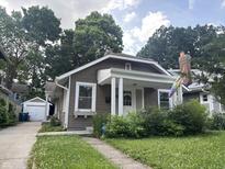 Charming brown home featuring a covered front porch and lovely landscaping at 4406 Carrollton Ave, Indianapolis, IN 46205