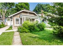 Charming single-story home with tan siding, a covered porch, and lush green landscaping at 4406 Carrollton Ave, Indianapolis, IN 46205