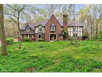 Inviting brick and Tudor home with a lush green lawn and mature trees at 5001 Woodrose Ln, Anderson, IN 46011
