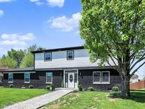 Charming two-story home boasts a striking black brick facade and a welcoming front yard with mature trees at 5354 Brendon Park Dr, Indianapolis, IN 46226