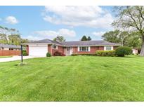 Charming single story red brick home with an attached garage and a lush green front yard at 8606 N Washington Blvd, Indianapolis, IN 46240