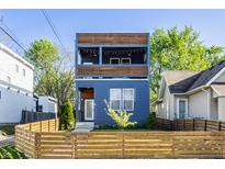 Charming three-story home with a striking blue facade, wood accents, and a welcoming fenced front yard at 1226 Cottage Ave, Indianapolis, IN 46203