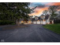 Stunning exterior view of a large home with a three-car garage and a spacious driveway during a vibrant sunset at 15617 Westfield Blvd, Carmel, IN 46033