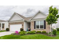 Well-maintained exterior with brick accents, a lush green lawn, and mature tree at 16044 Loire Valley Dr, Fishers, IN 46037