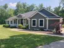 Charming single-story home with a covered porch, dark siding, and manicured landscaping on a sunny day at 5607 E 500 N, Greenfield, IN 46140